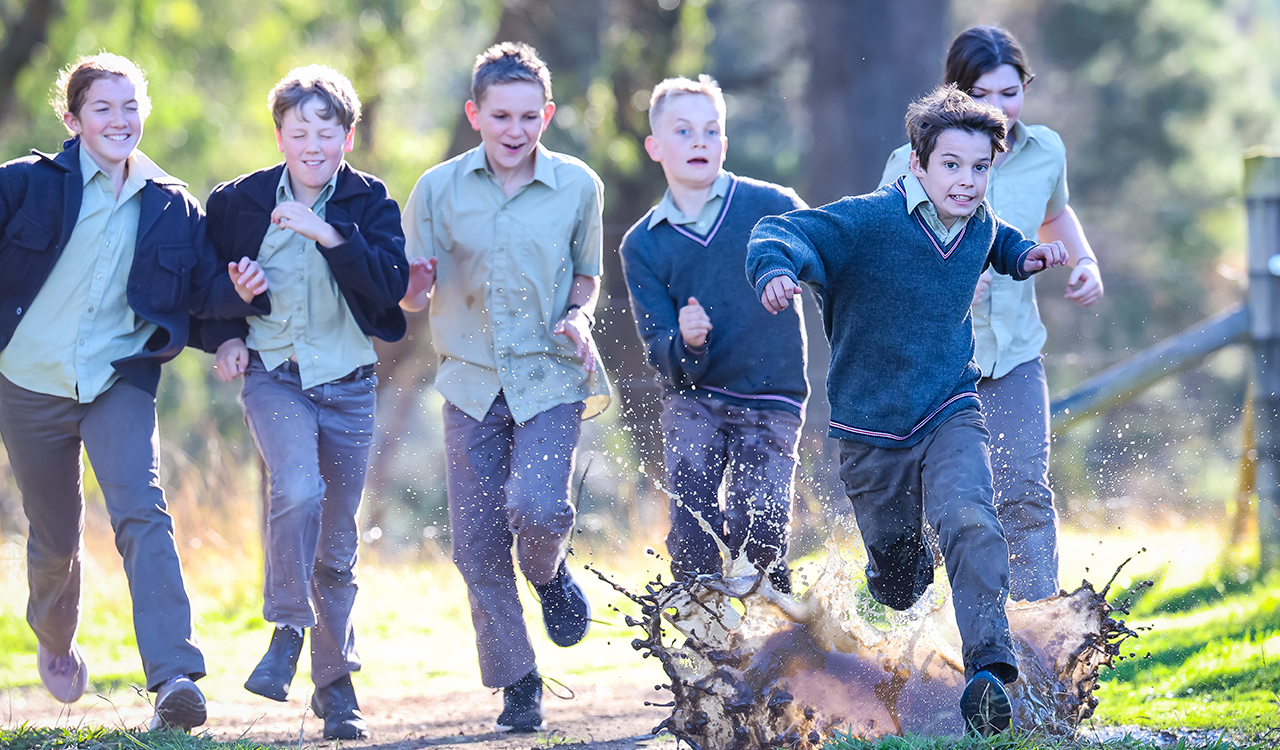 Students in their school uniform running through mud